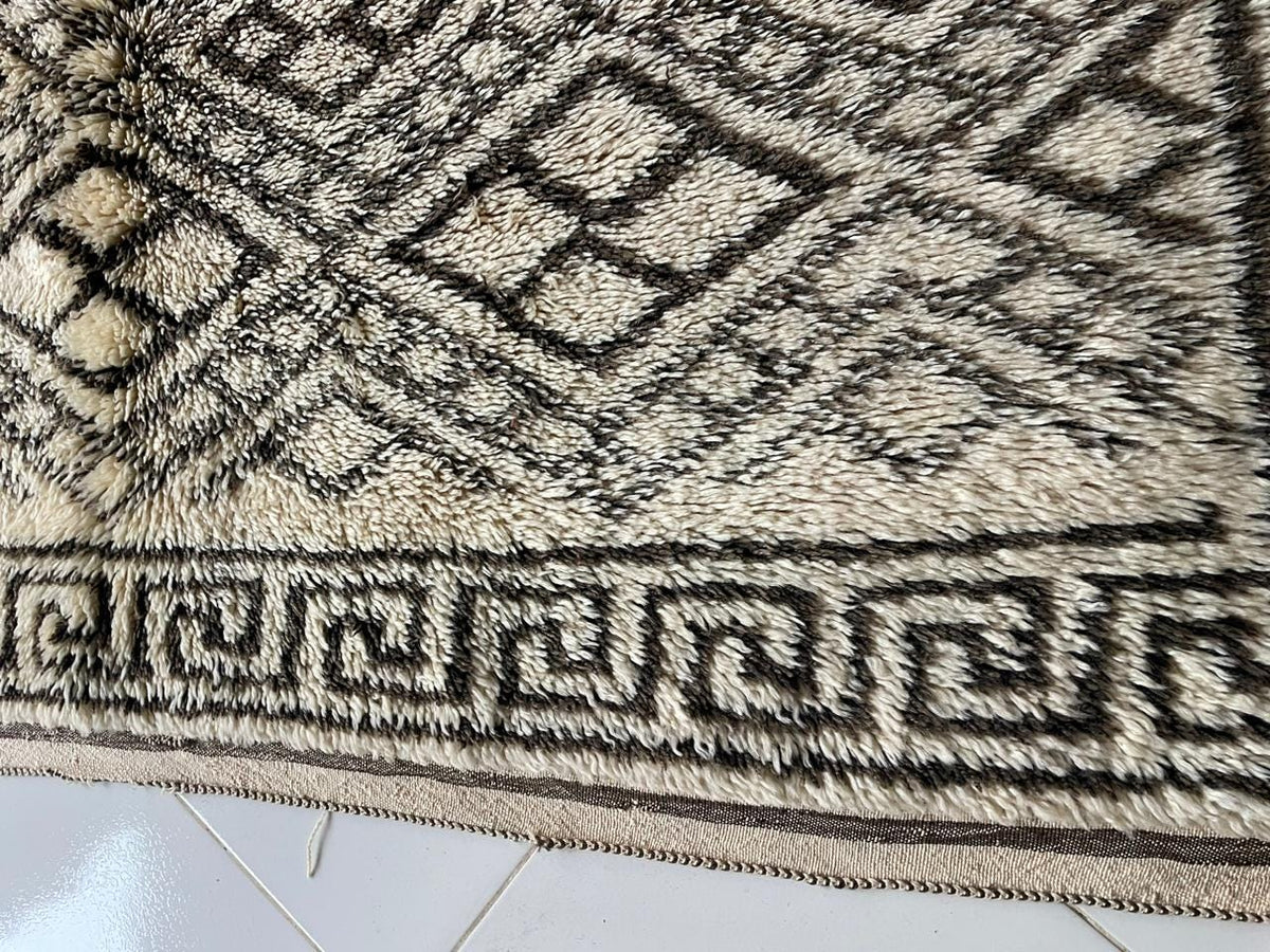Close-up detail of a beige and black rug highlighting diamond shapes and an intricate design.