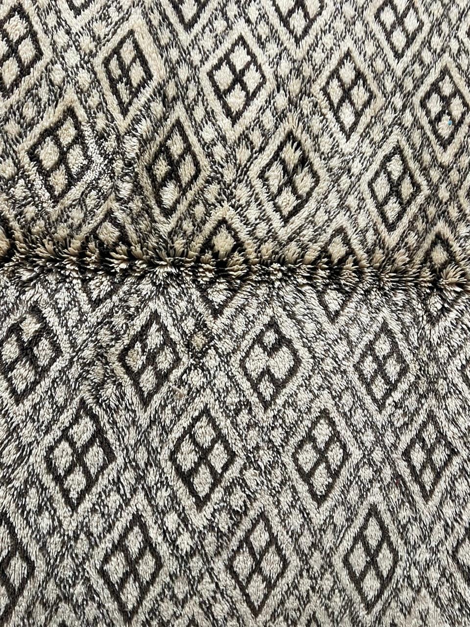 Close-up detail of a vintage Moroccan rug in gray and cream with a diamond pattern and woven texture.