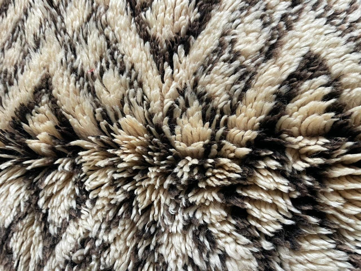 Close-up detail of a vintage Moroccan rug in cream and black with a geometric pattern.