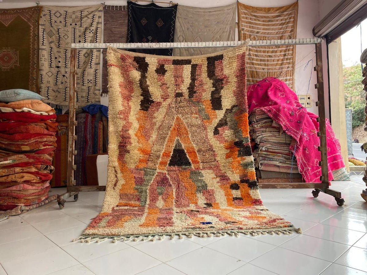 Lifestyle shot of a vintage Moroccan rug with abstract patterns in orange, brown, and black.