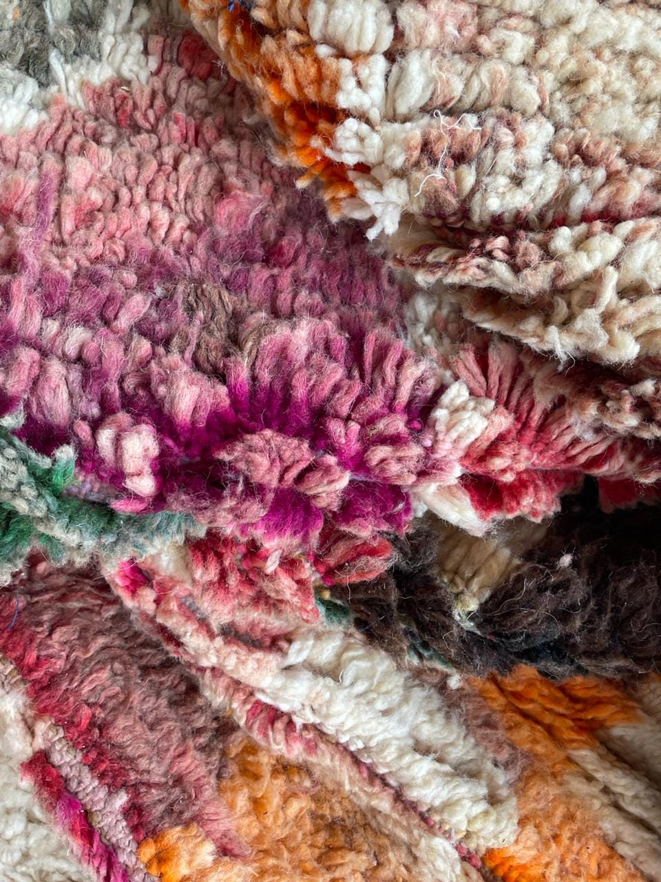 Detail view of a vintage Moroccan rug showcasing purple, orange, and cream colors.