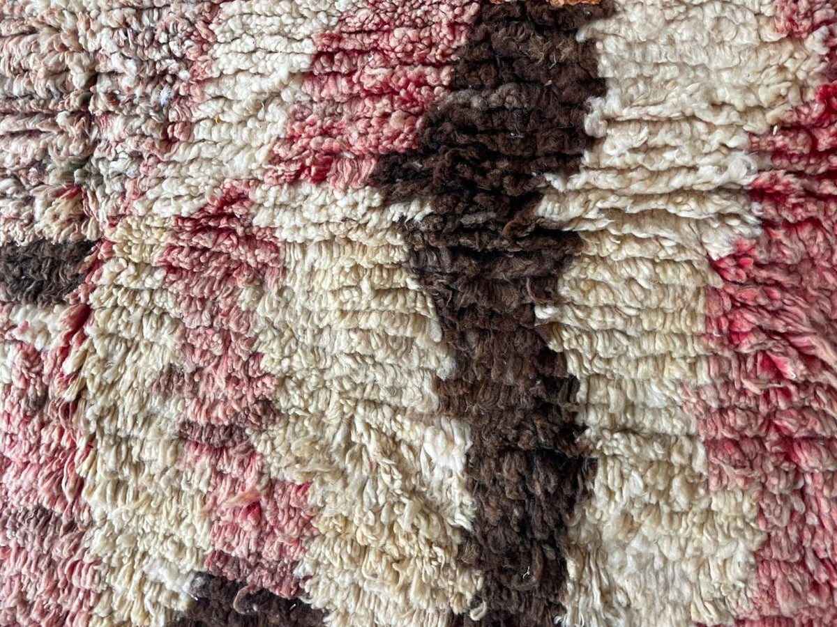 Detail view of a vintage Moroccan rug with orange, purple, and cream colors.