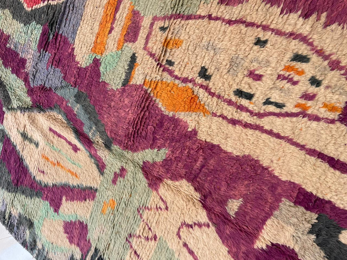 Close-up detail of a vintage Moroccan rug highlighting its geometric patterns in purple, green, and orange.