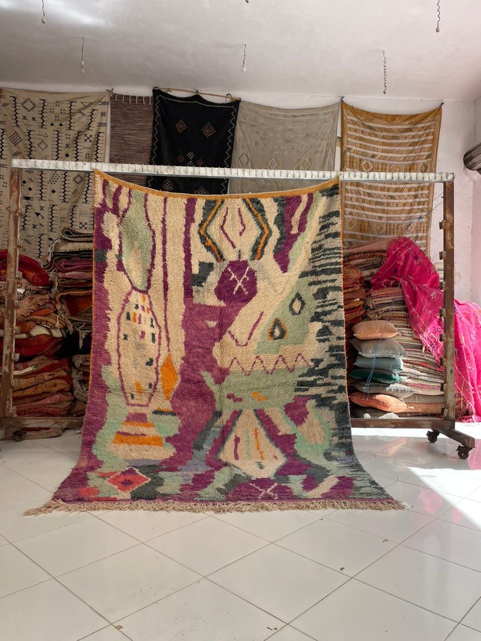 Lifestyle shot of a vintage Moroccan rug featuring geometric patterns in purple, green, and orange.