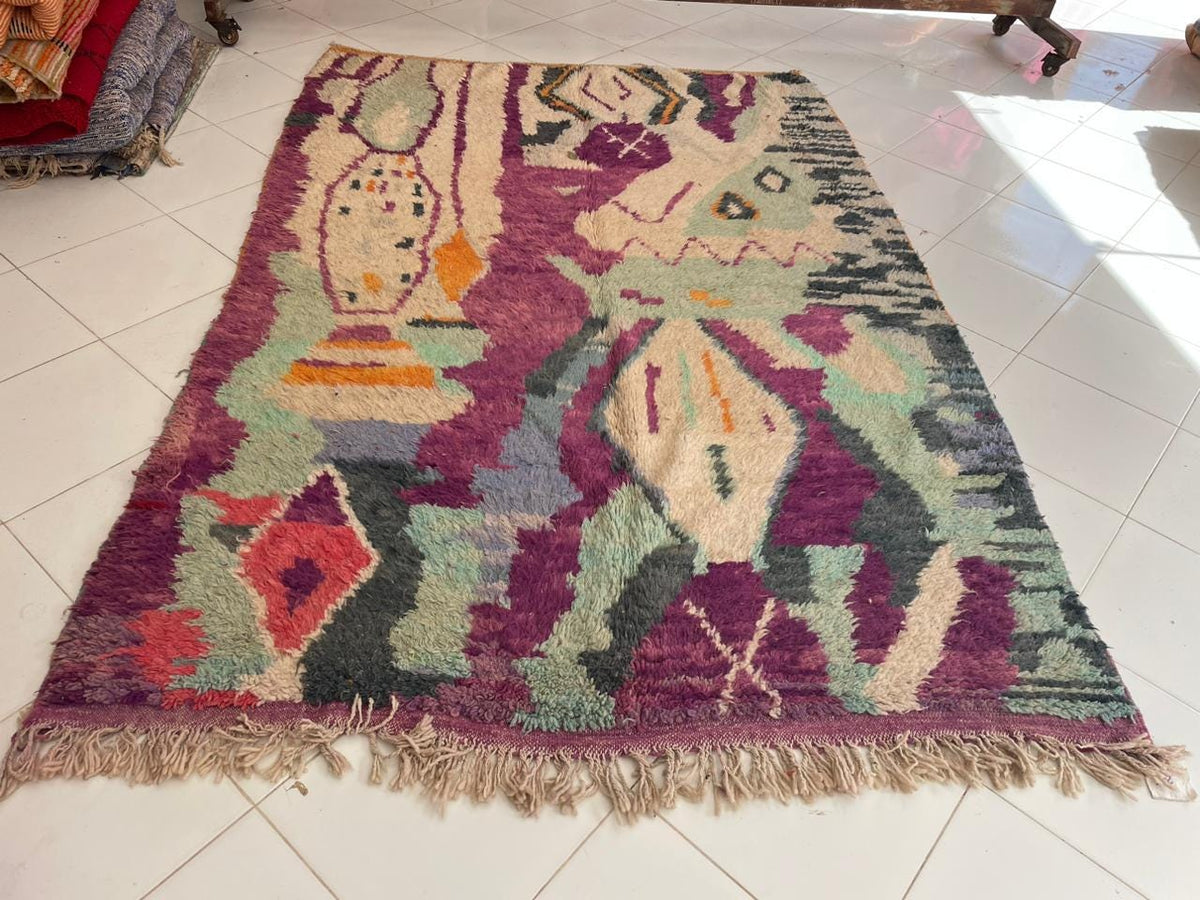 Close-up detail of a vintage Moroccan rug showcasing its geometric patterns in purple, green, and orange.
