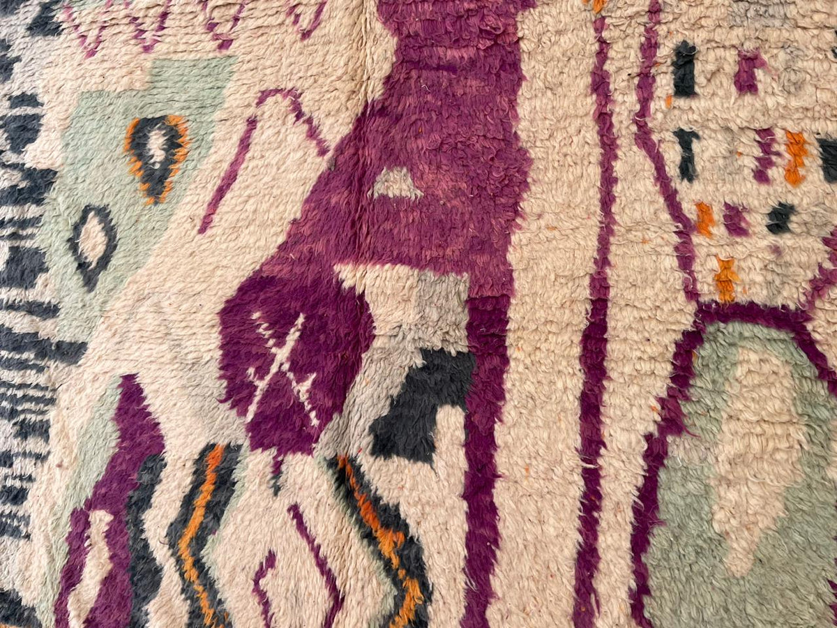 Close-up detail of a vintage Moroccan rug with geometric patterns in purple, green, and orange.