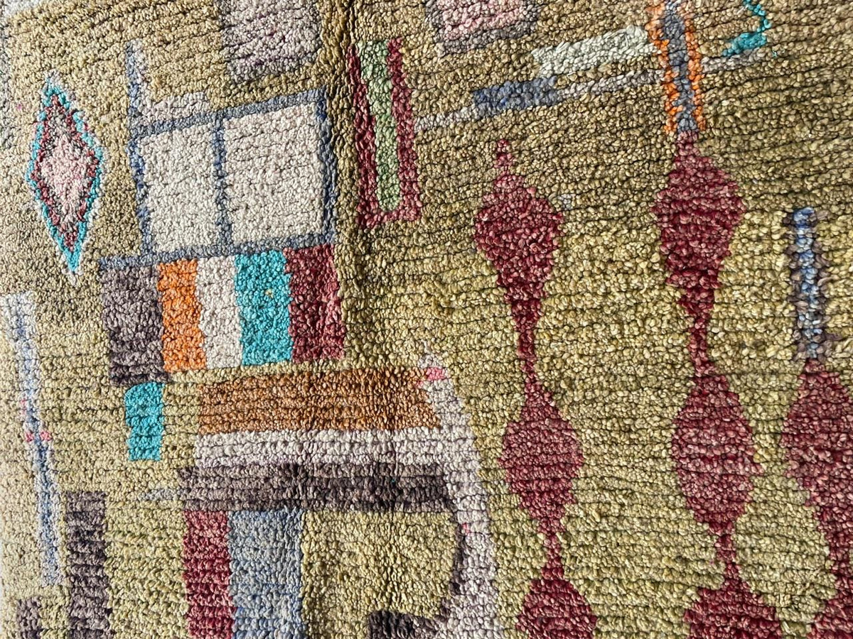 Side view of a vintage Moroccan rug showcasing geometric patterns and a textured surface in gold, red, and blue.