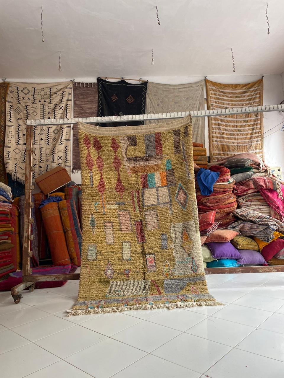 Lifestyle shot of a vintage Moroccan rug with various patterns in yellow, red, and blue.