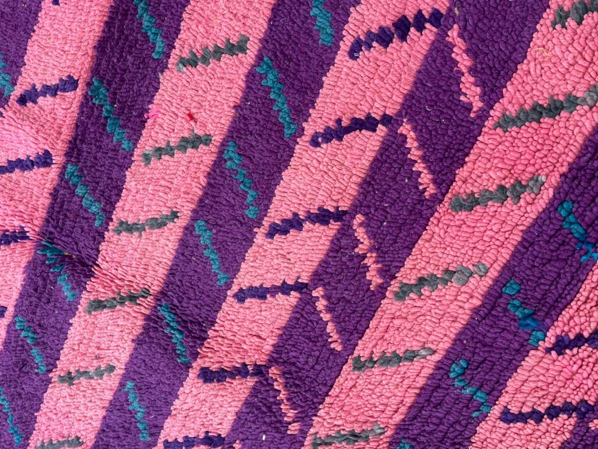 Detail shot of a pink Moroccan rug highlighting its geometric pattern and textured surface.