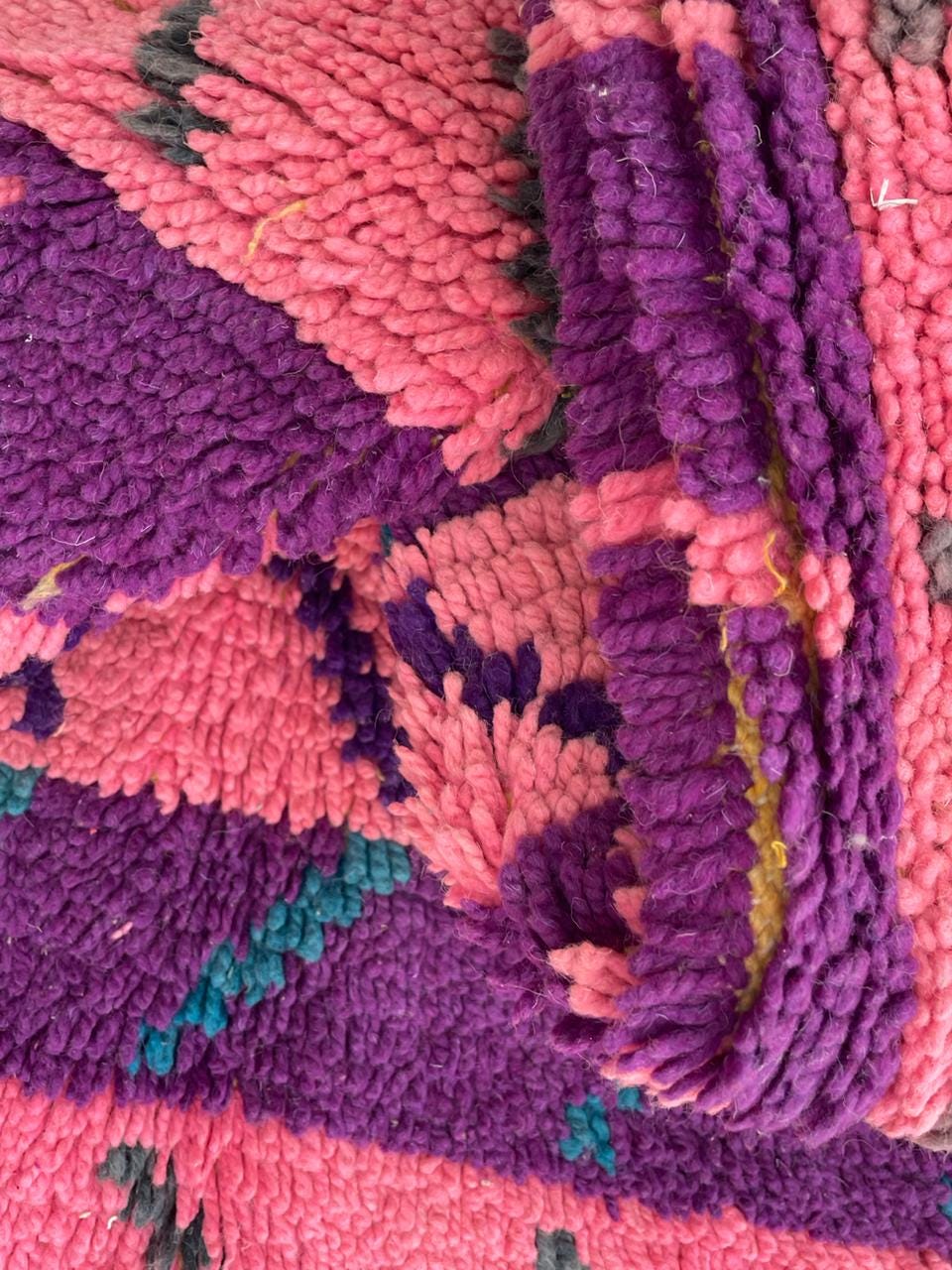 Close-up of a pink wool rug showcasing a textured weave and fringe edge.