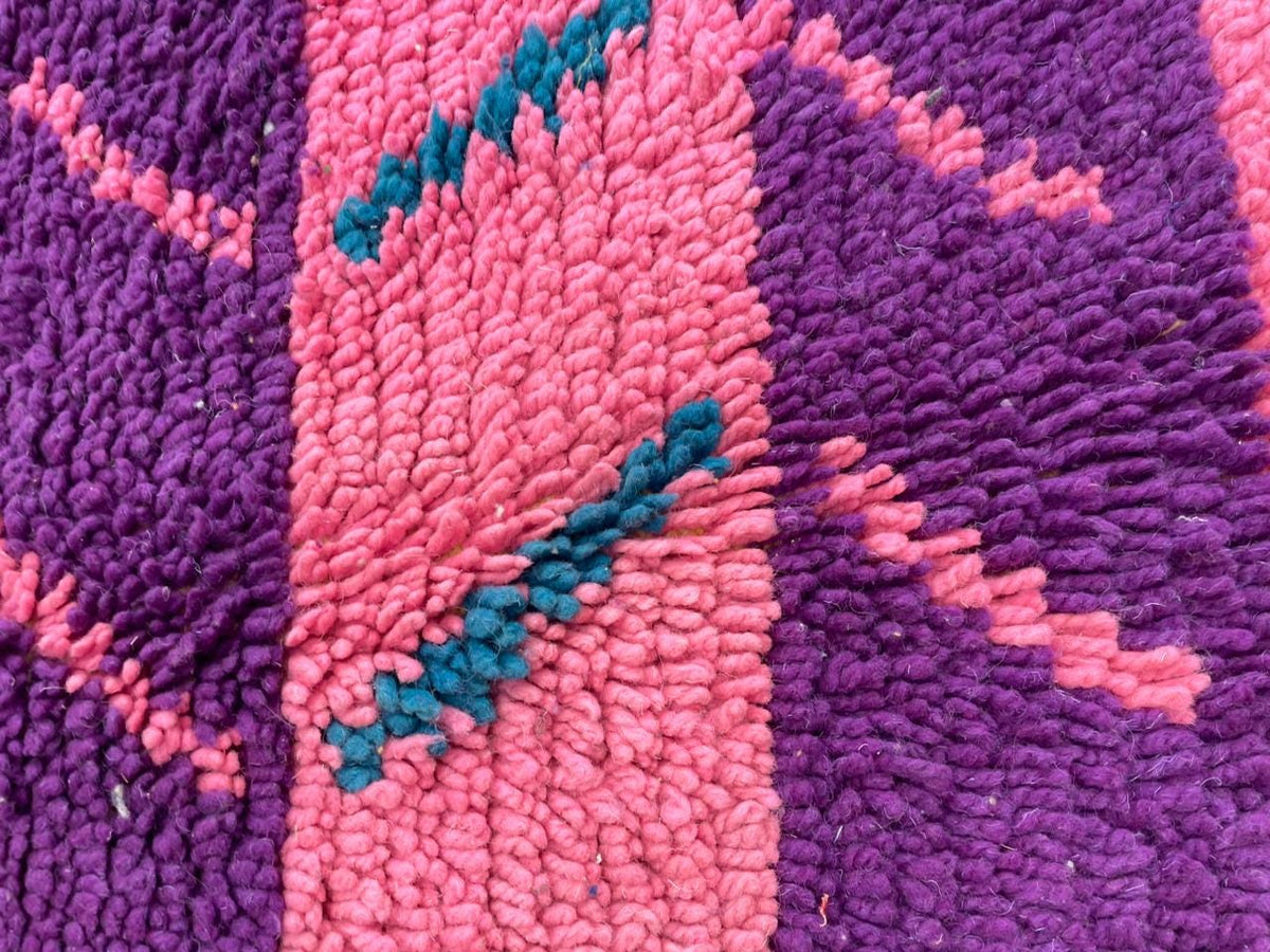 Detail view of a pink Moroccan rug featuring a colorful design and soft texture.