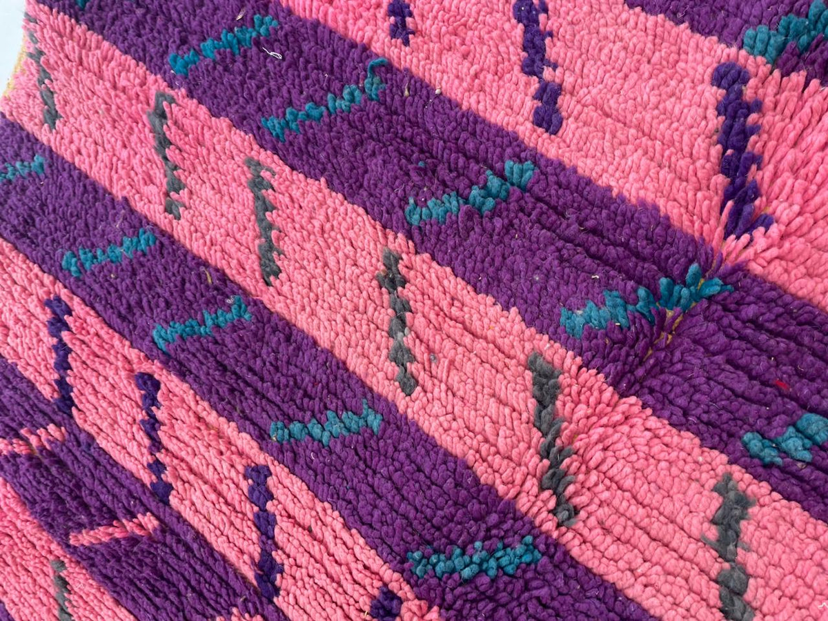 Close-up detail of the textured fabric and pattern of a pink vintage Moroccan rug.