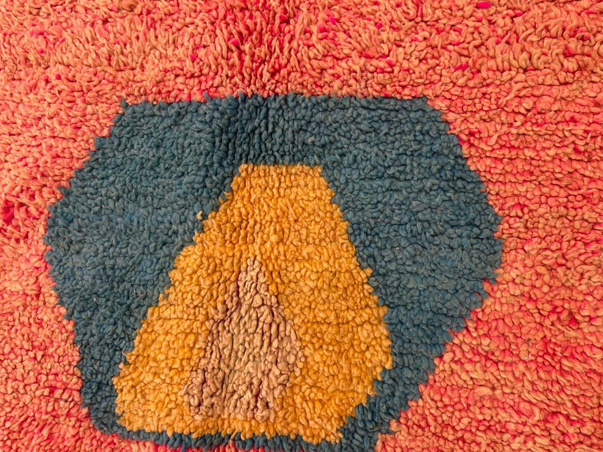 Detail shot of colorful patterns and textured surface on the pink Moroccan rug.