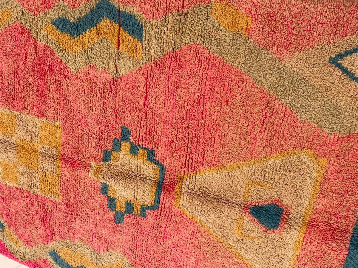 Close-up of geometric patterns and textured surface on the pink Moroccan rug.