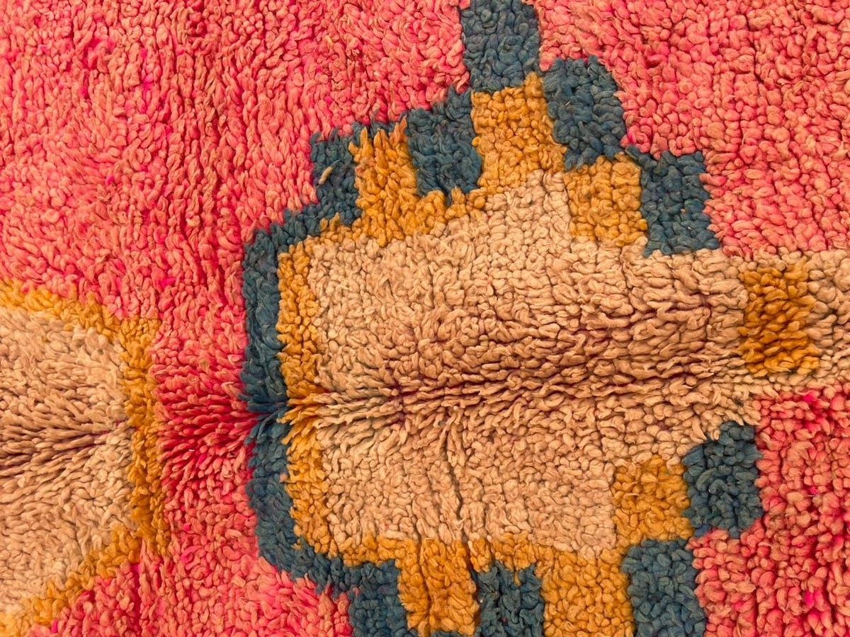 Close-up detail of the textured fibers and colorful designs of the pink Moroccan rug.