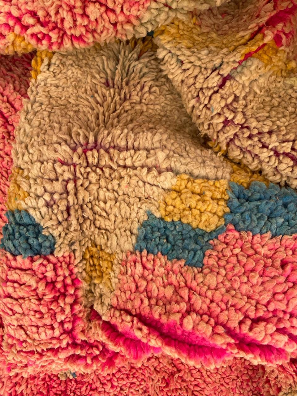 Detail view of the intricate design and soft texture of the vintage Moroccan rug in red, gold, and blue.