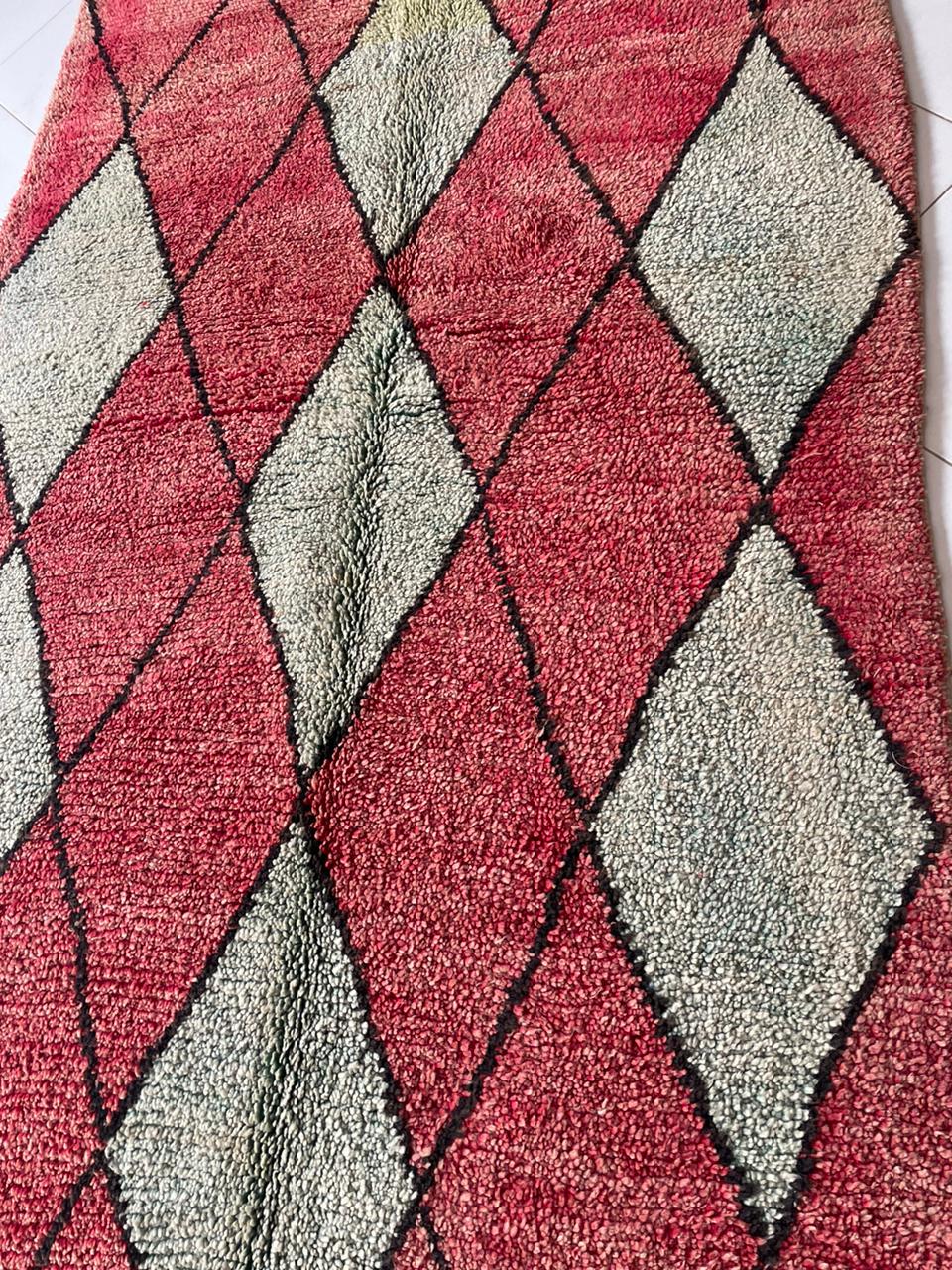Detail close-up of a colorful Moroccan rug featuring an abstract design in red, green, and black.