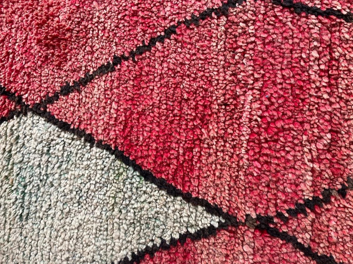 Detail close-up of a red Moroccan rug featuring a diamond pattern with black and white accents.