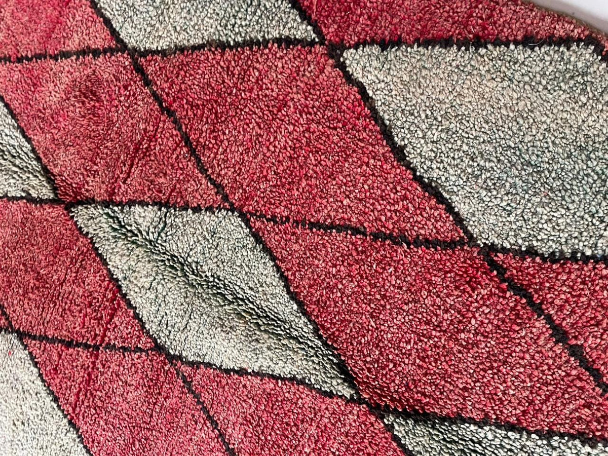 Detail close-up of a red Moroccan rug showcasing a diamond pattern with black and white accents.