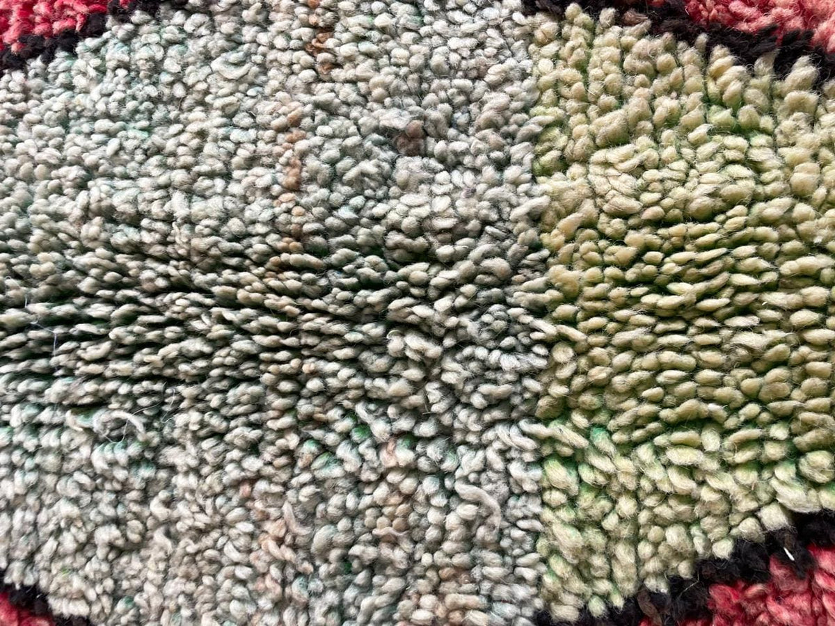 Detail close-up of a red Moroccan rug with a diamond pattern and textured surface.