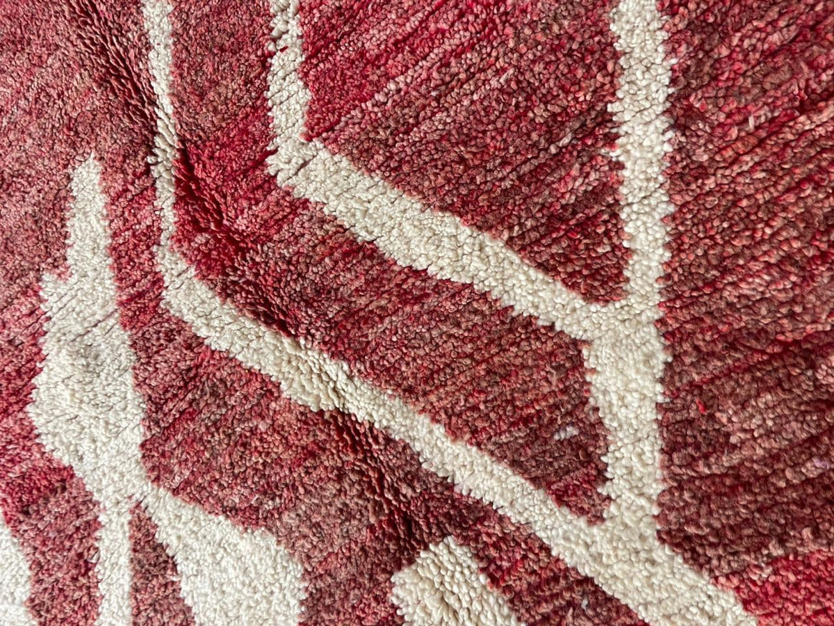 Detail shot of a red Moroccan rug with a geometric pattern and wool texture.