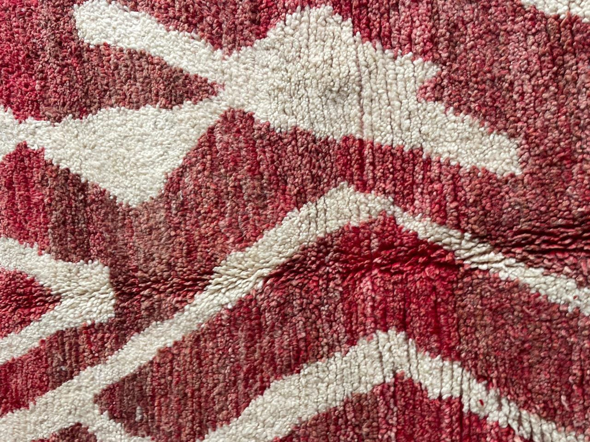 Detail view of a red Moroccan rug showcasing a geometric pattern and wool texture.