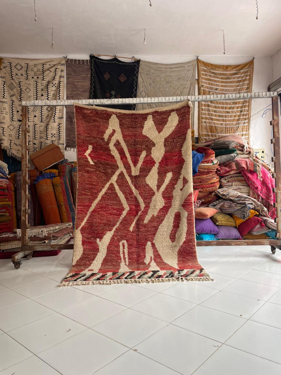Lifestyle shot of a red Moroccan rug with geometric patterns in a natural setting.