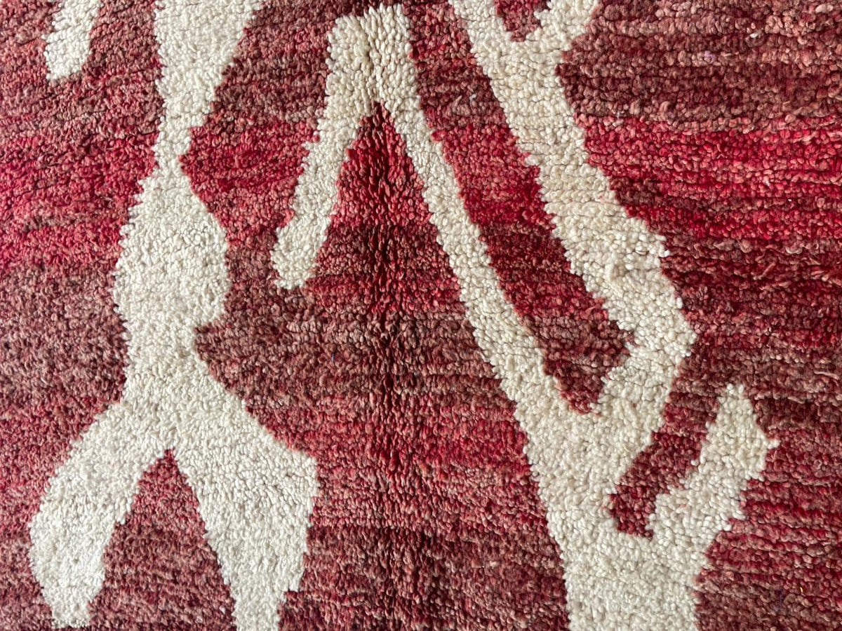Close-up detail of a red Moroccan rug showcasing intricate patterns and a soft texture.