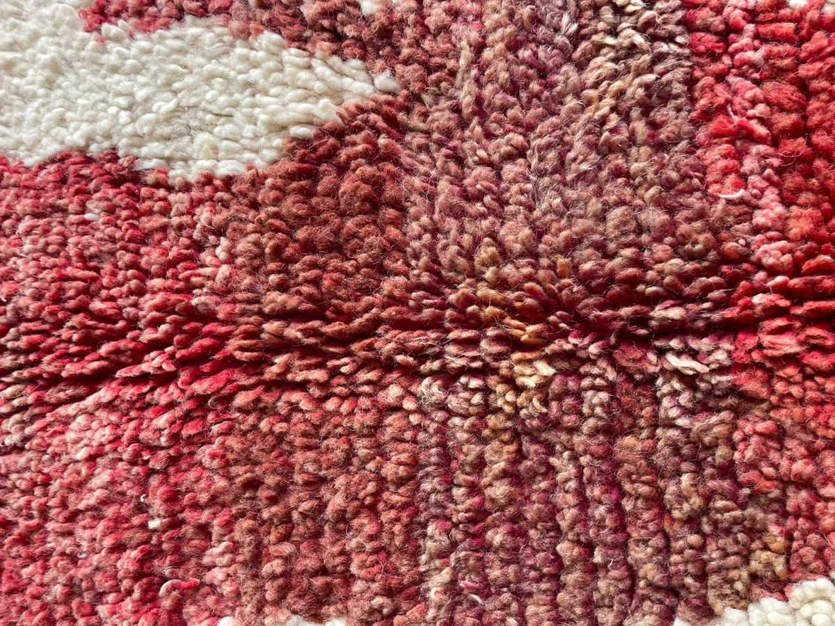 Close-up of a red Moroccan rug displaying a wavy pattern and thick pile.