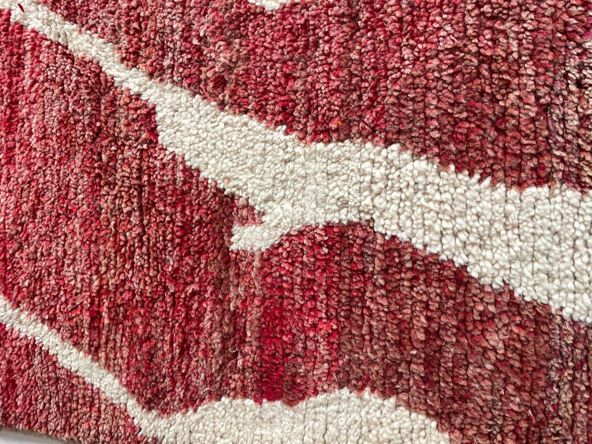 Detail view of a red Moroccan rug featuring an abstract design and soft texture.
