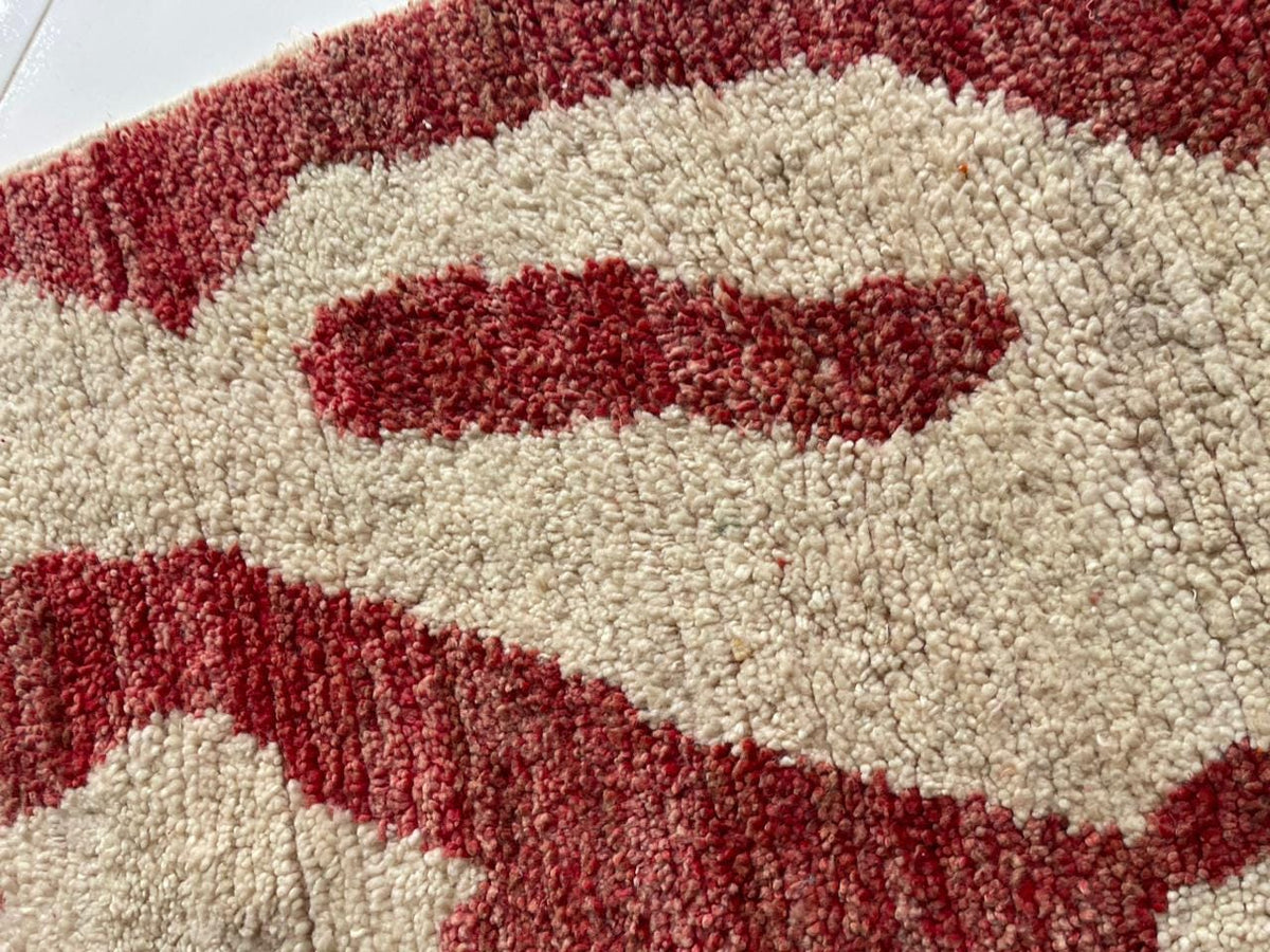 Detail shot of a red Moroccan rug with curved shapes and plush fibers.