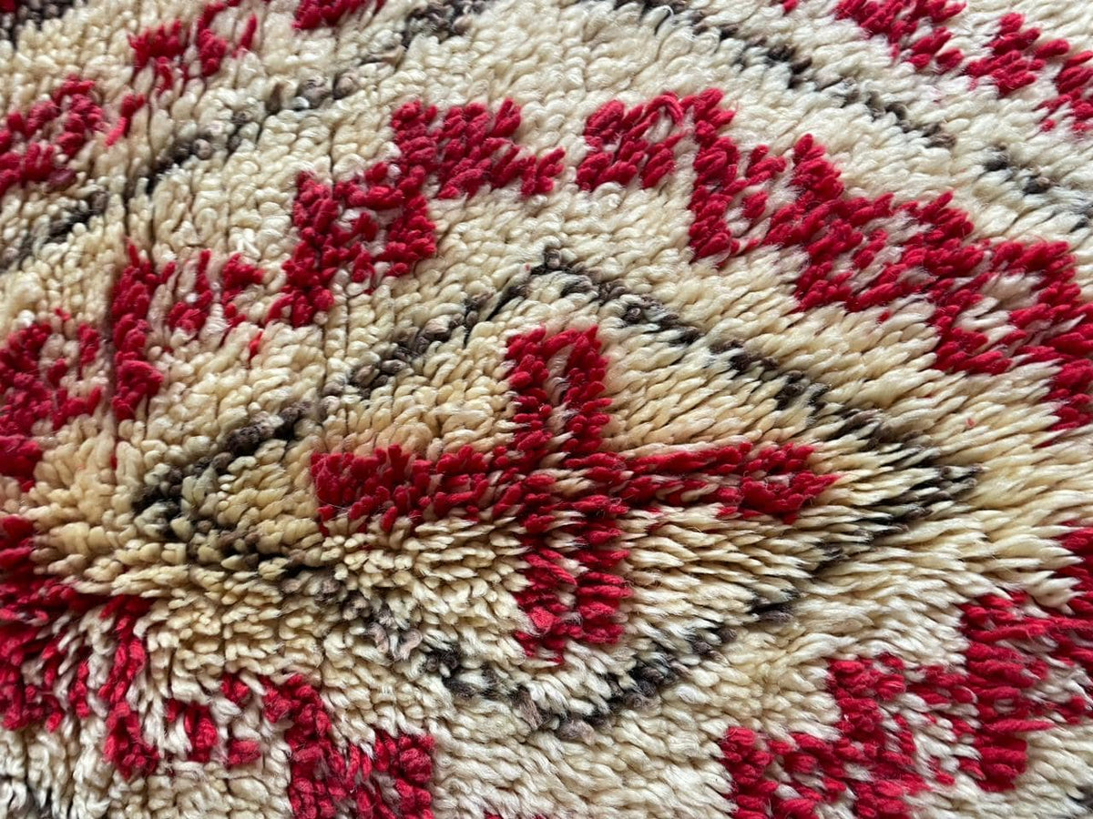 Detail view of a red Moroccan rug featuring cross patterns and soft wool.