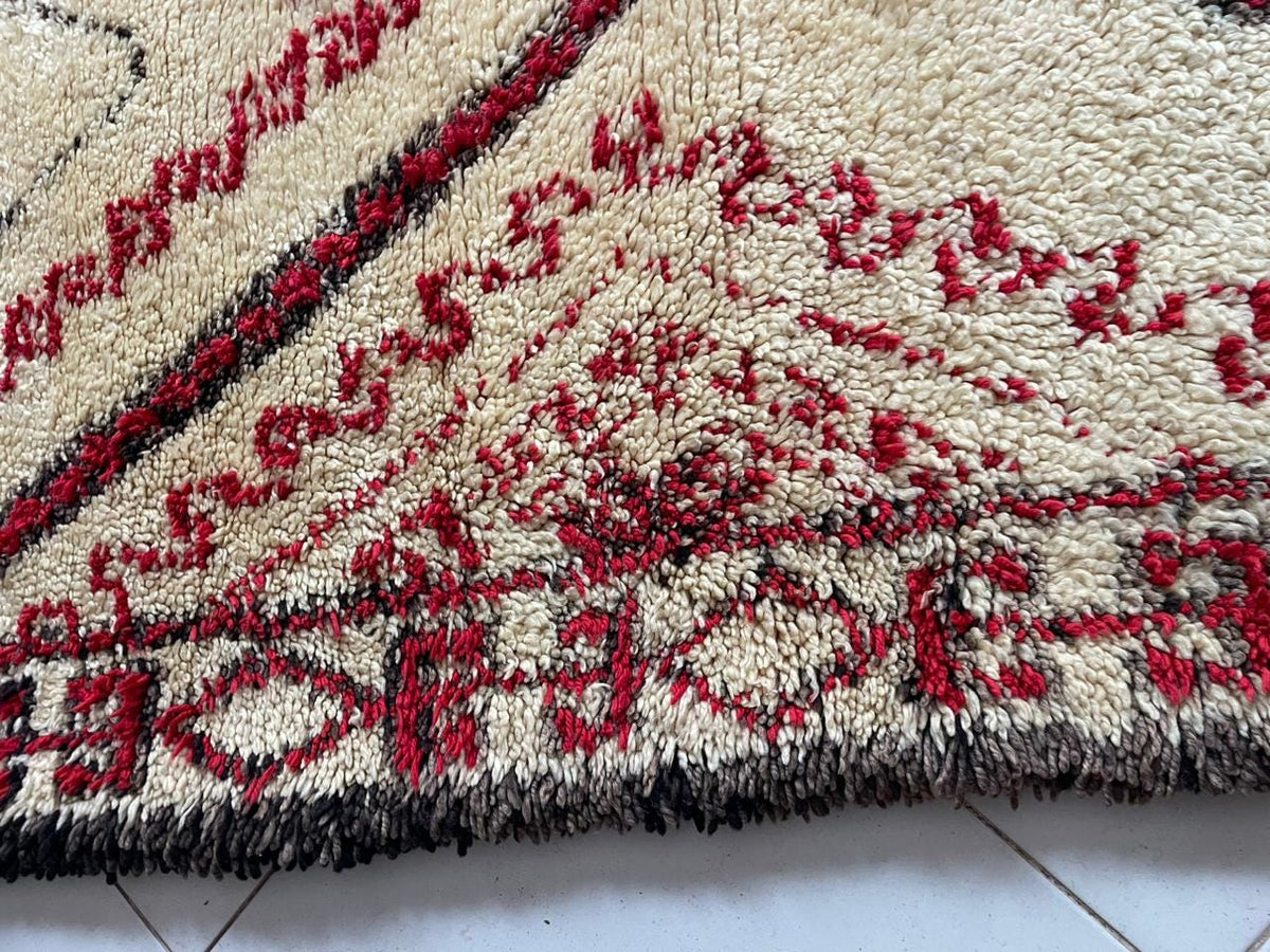 Close-up of geometric patterns on a red Moroccan rug with textured wool.