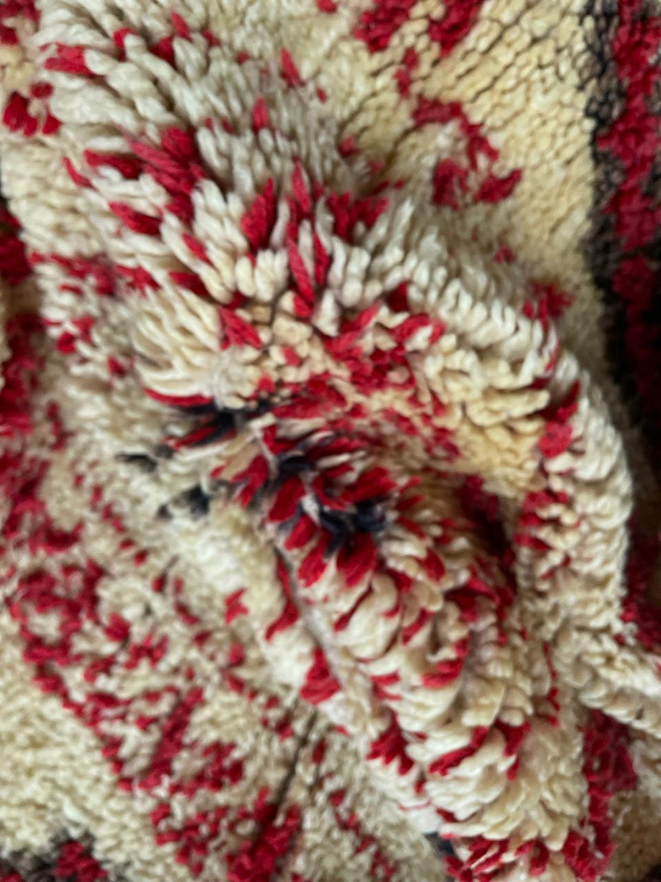 Detail view of a red Moroccan rug showcasing intricate designs and texture.