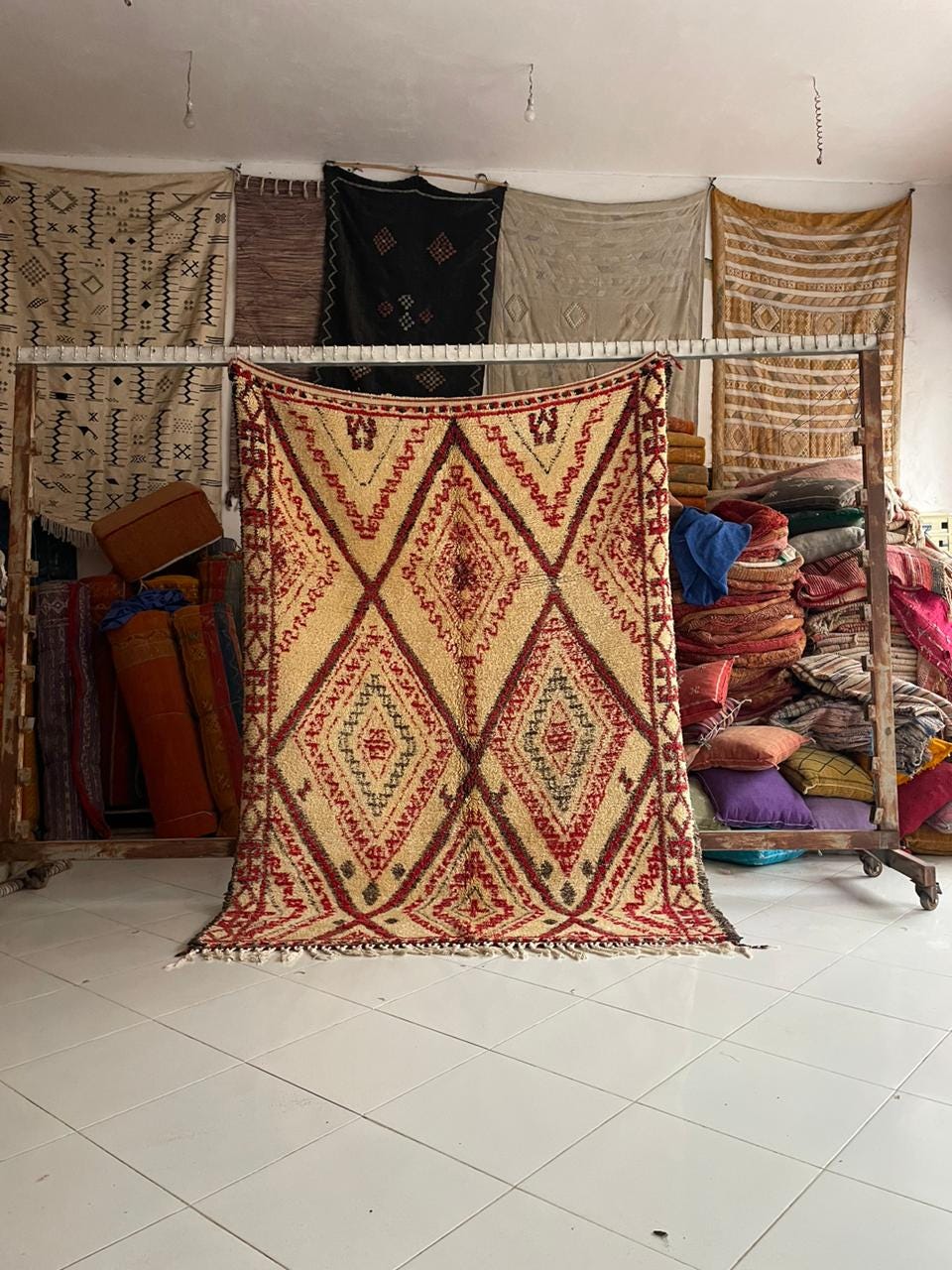 Lifestyle shot of a red Moroccan rug with geometric patterns and fringe edges.