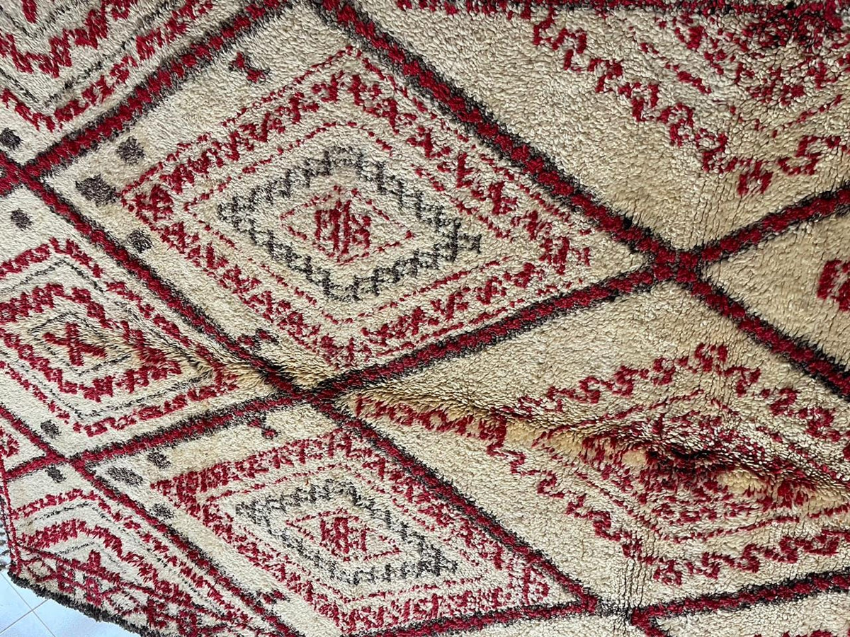 Close-up detail of diamond motifs on a red Moroccan rug with woven texture.