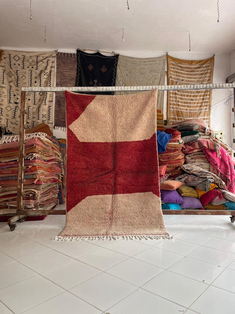 Lifestyle shot of a Moroccan rug featuring red and beige patterns displayed in a natural setting.