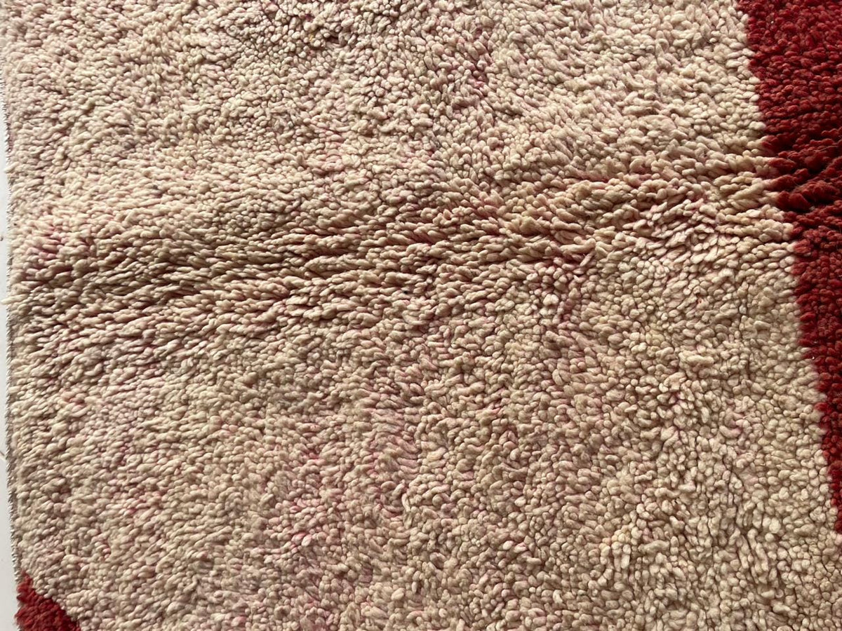 Detail close-up of a vintage Moroccan rug showcasing its textured surface and geometric pattern.