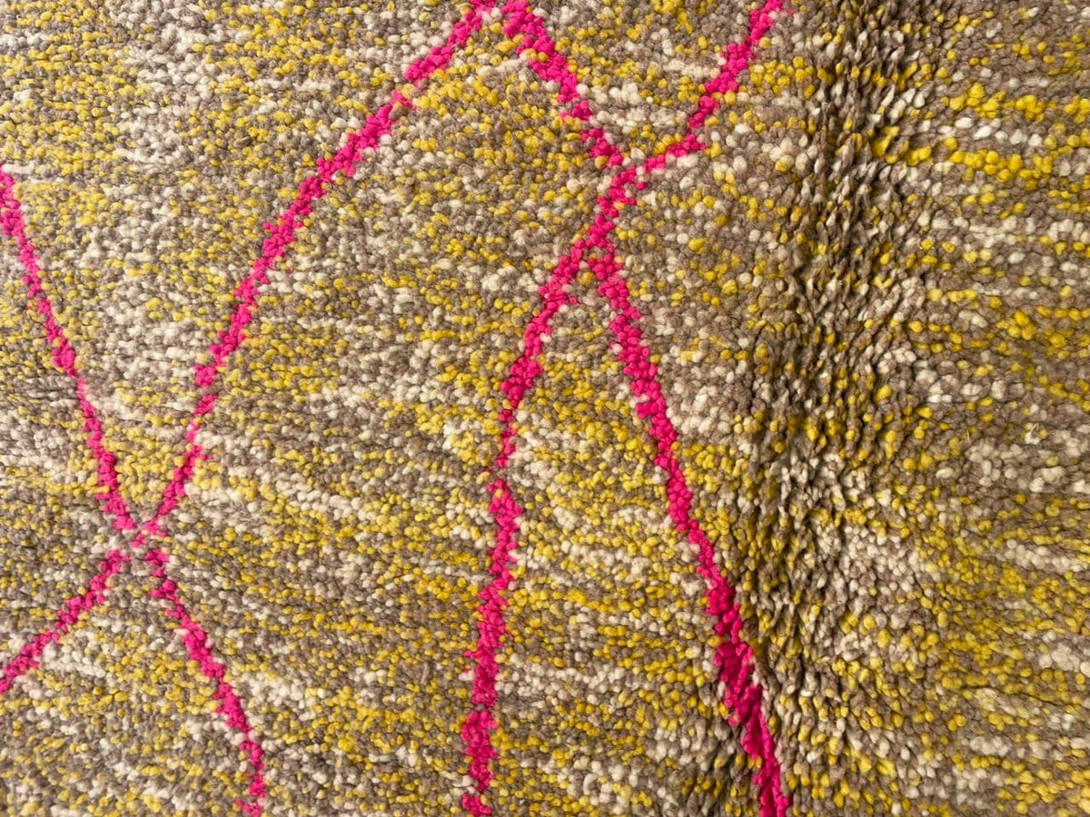 Detail close-up of a vintage Moroccan rug focusing on texture and pattern details in gold and red.