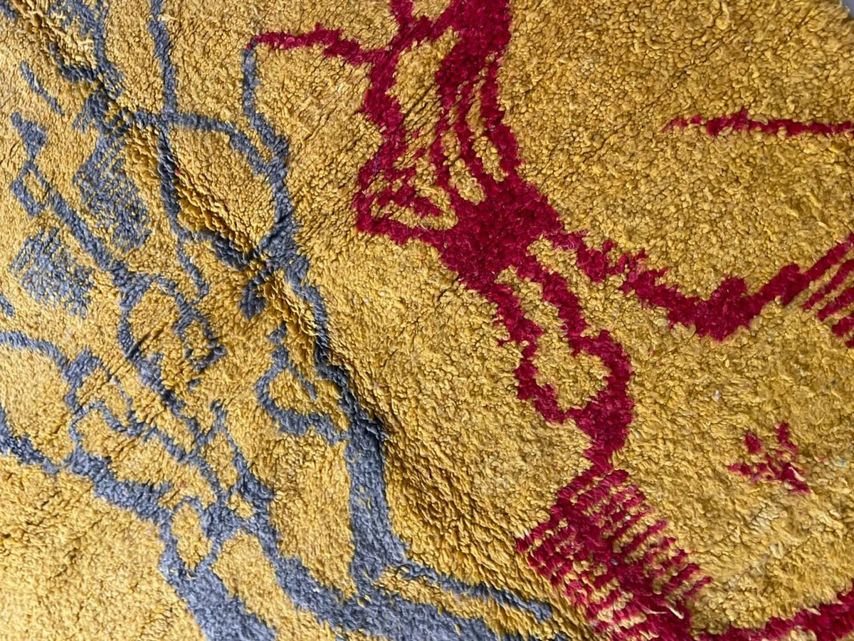 Close-up of a yellow Moroccan rug highlighting geometric patterns and a textured surface.