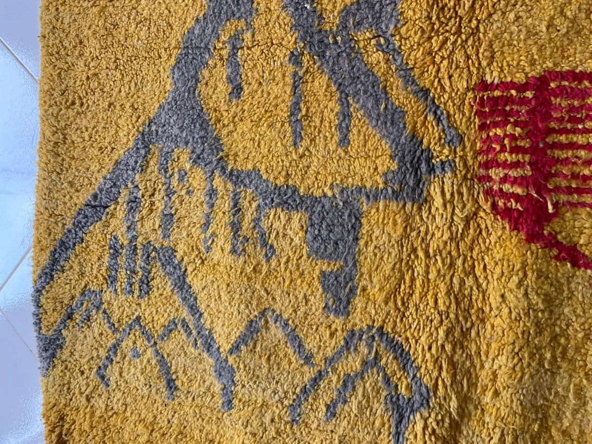 Close-up detail of a yellow Moroccan rug displaying an abstract design and soft texture.