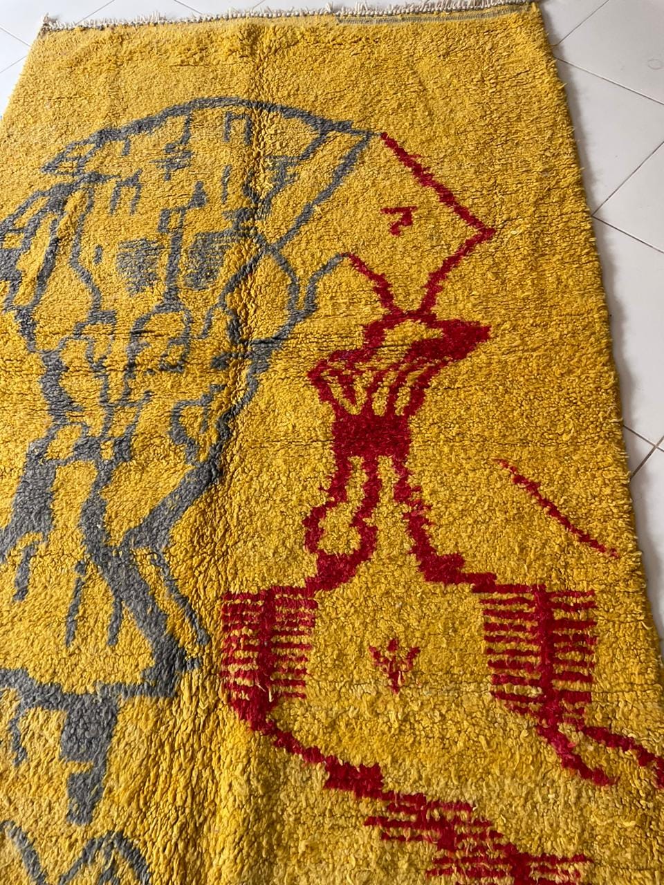 Close-up detail of a yellow Moroccan rug featuring mountain motifs and a thick pile.