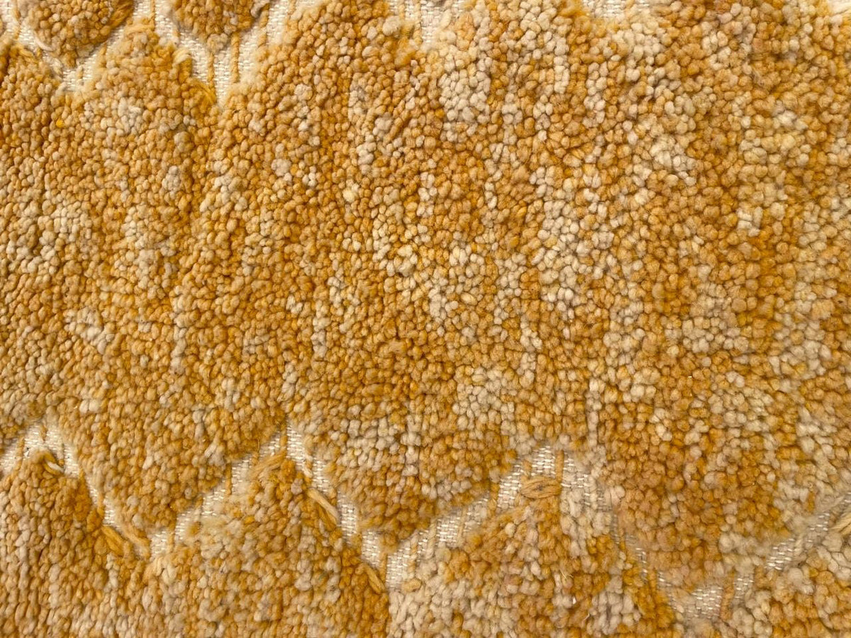 Close-up detail of a yellow rug displaying a geometric pattern with a soft texture.