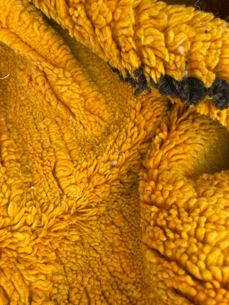 Detail shot of a yellow wool rug featuring a textured pattern and thick weave.