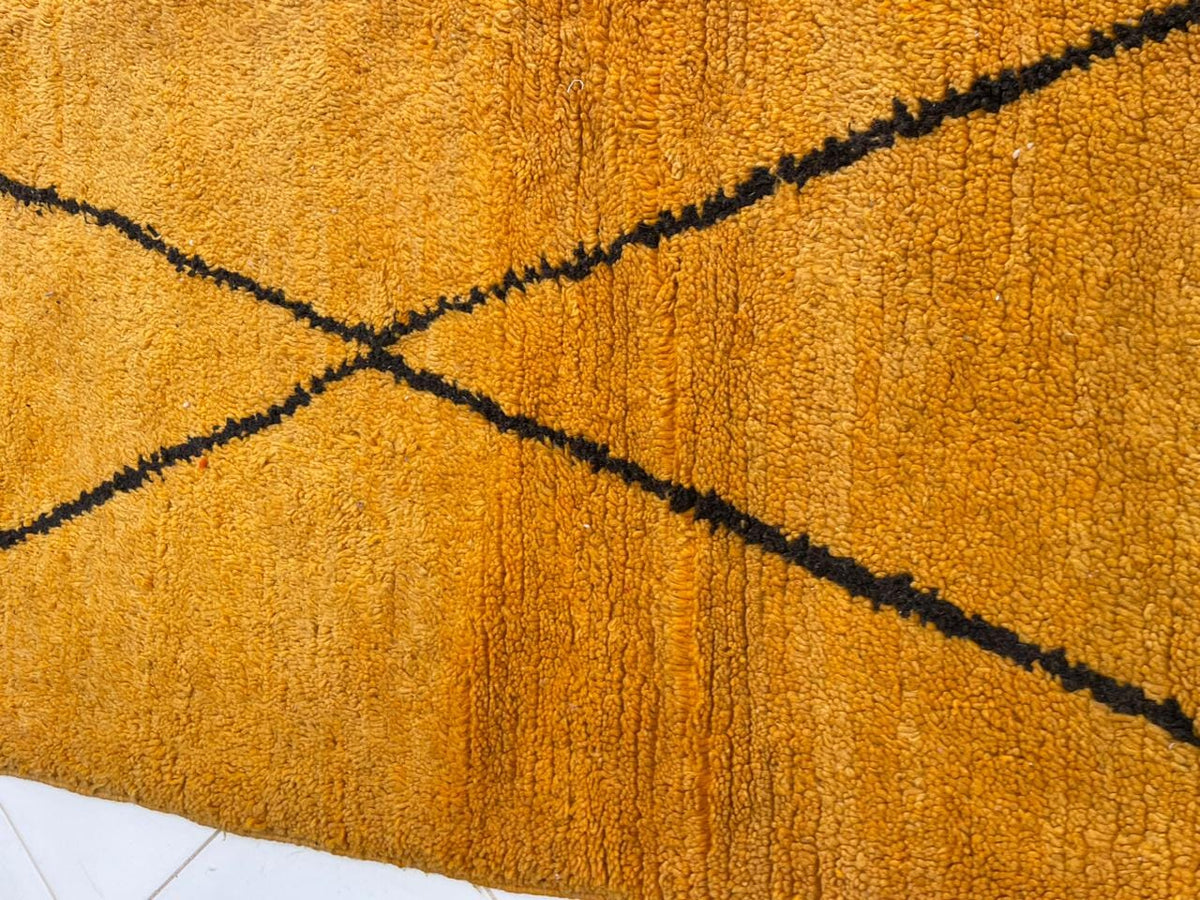 Detail shot of a yellow wool rug with soft fibers and a line pattern.