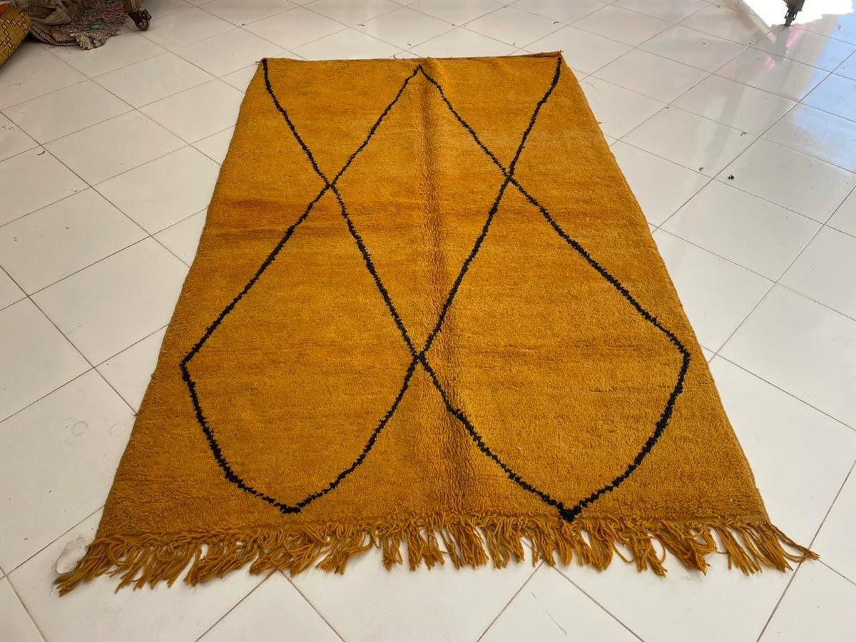 Top view of a yellow Moroccan rug featuring a geometric pattern and fringe edges.