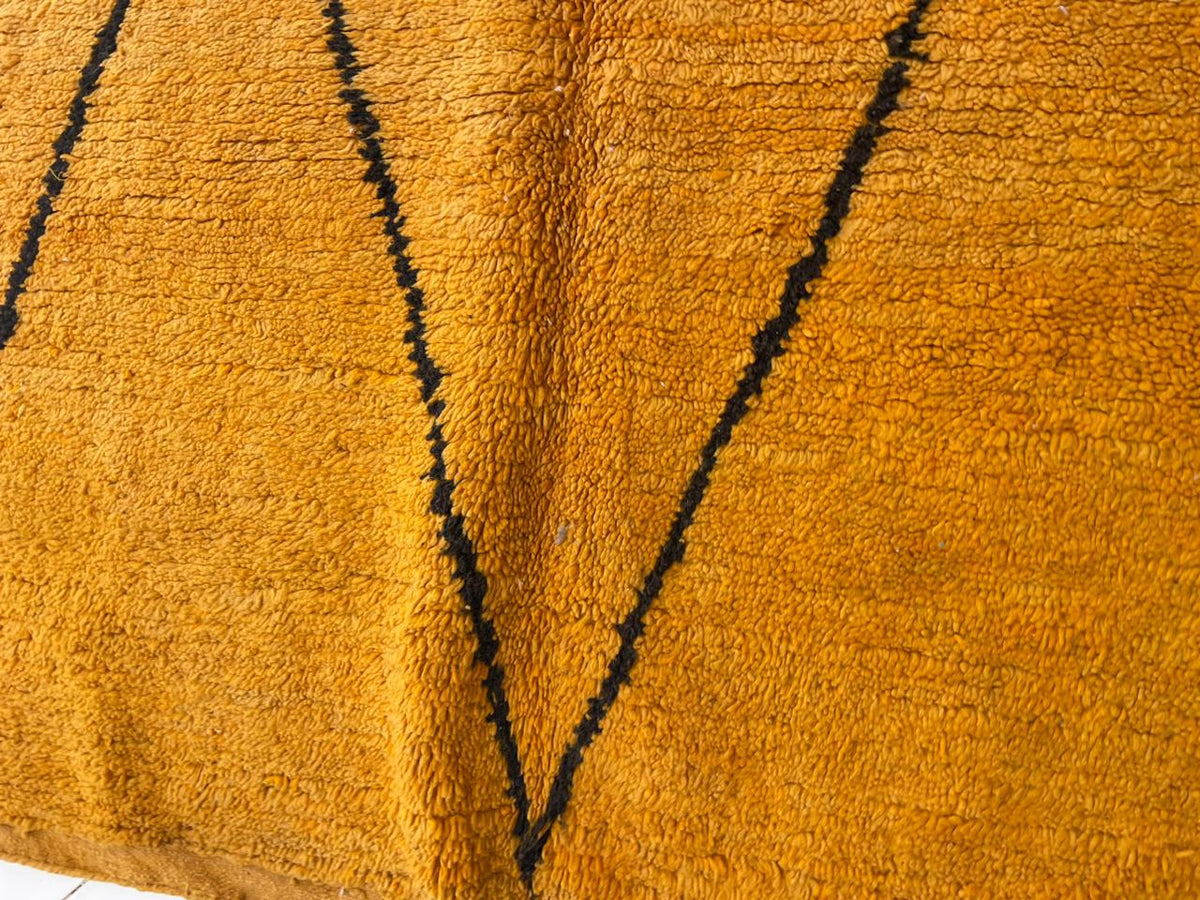 Close-up detail of a yellow Moroccan rug highlighting its geometric pattern and soft texture.