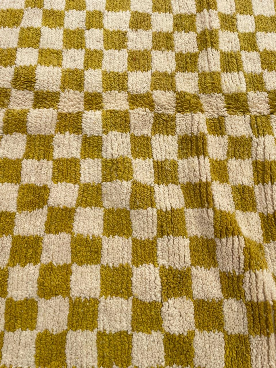 Close-up detail of a yellow Moroccan rug showcasing its checkered pattern and soft texture.