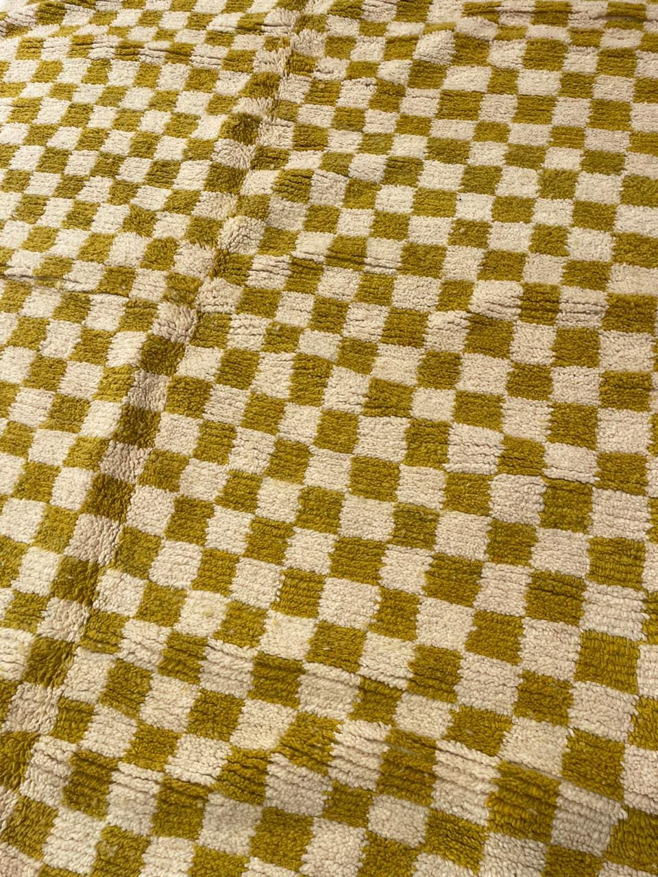 Close-up detail of a yellow Moroccan rug highlighting its checkered pattern and soft texture.