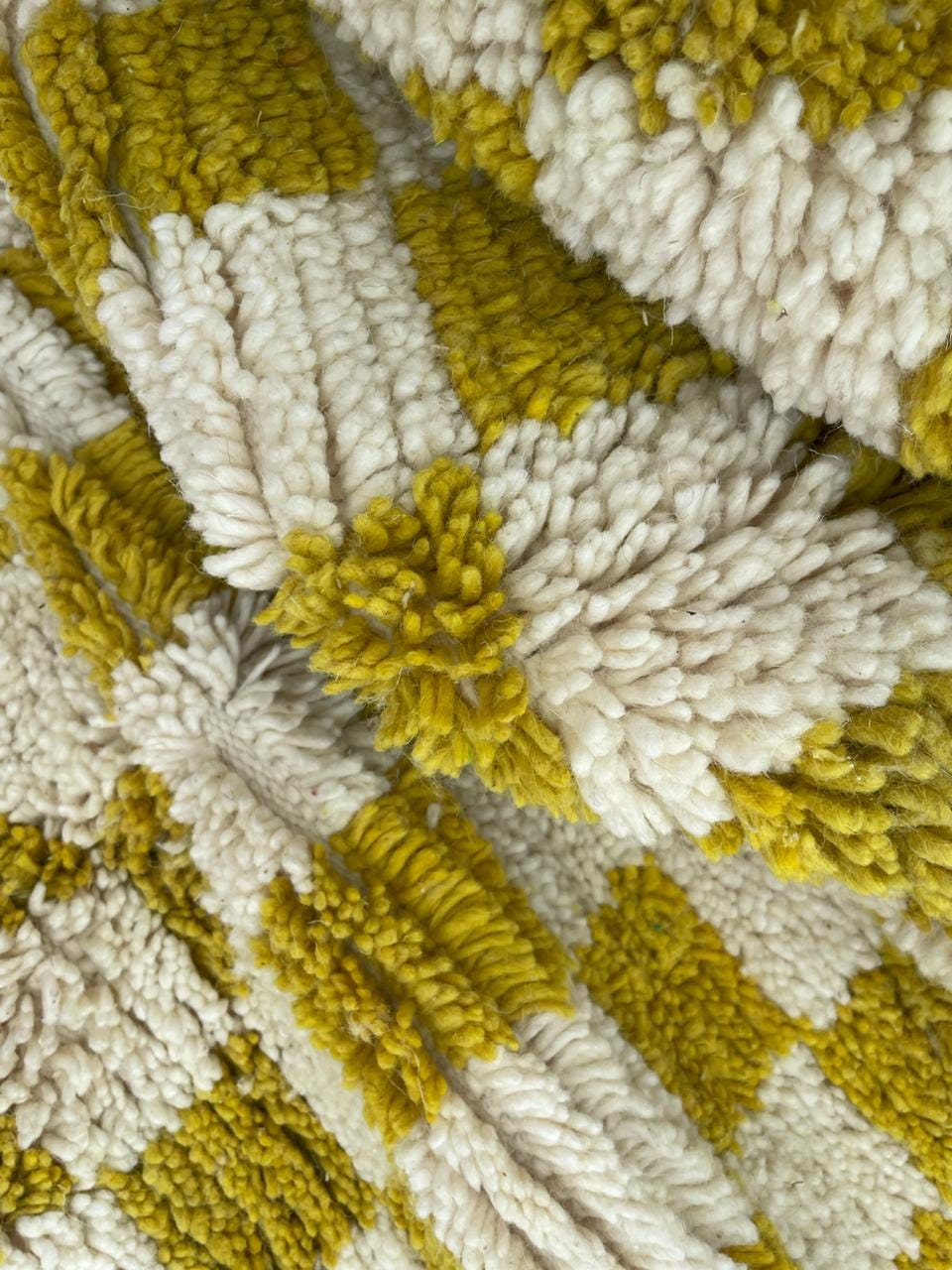 Detail shot of a yellow wool rug with a textured pattern and checkered design.